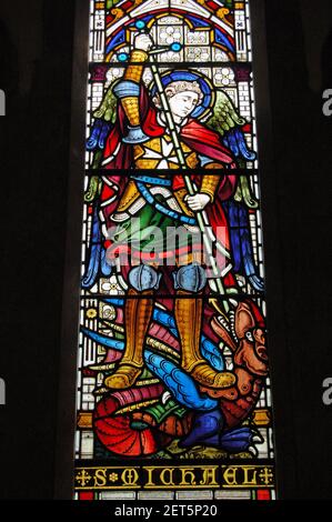 Victorian stained glass window depicting the saint Archangel Michael slaying a dragon with his sword. Window created in the mid 19th century and is on Stock Photo