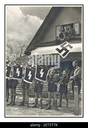 1930's Vintage Hitler Youth Nazi Propaganda image of Hitler Jugend boys on a Nazi themed trip, blowing a fanfare on parade displaying swastika and military symbols Germany 1934 Stock Photo