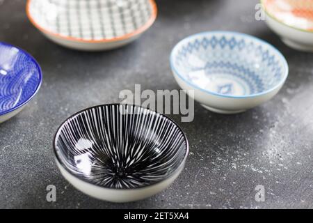 A closeup shot of colorful differently patterned bowls on the dark grunge table surface Stock Photo