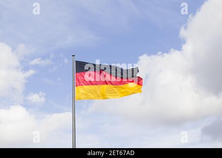 A German national flag, red, black, and yellow colors on the blue sky background. Stock Photo