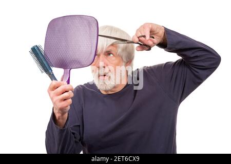 Horizontal shot of an old man giving himself a haircut during the pandemic.  White background. Stock Photo