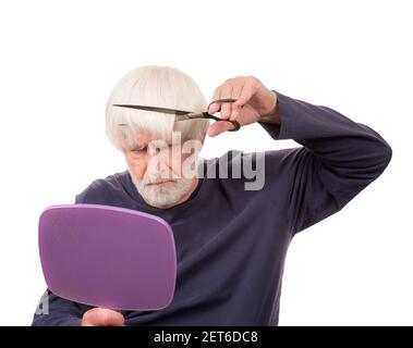 Horizontal shot of an old man giving himself a haircut during the pandemic.  White background. Stock Photo