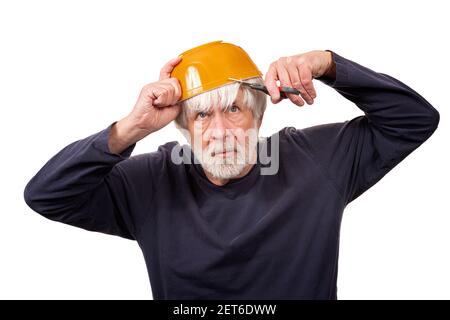 Horizontal shot of an old man giving himself a haircut using a yellow bowl on his head during the pandemic.  White background. Stock Photo