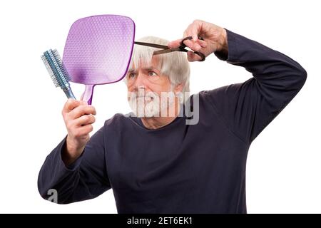 Horizontal shot of an old man giving himself a pandemic haircut.  White background. Stock Photo