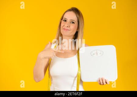 Beautiful smiling woman with scales over yellow background Stock Photo
