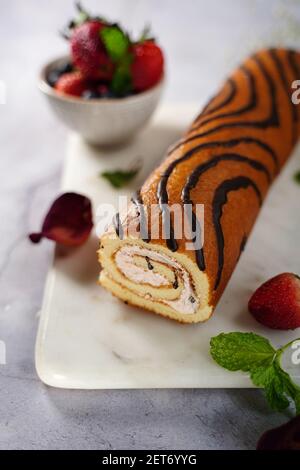 Strawberry Swiss roll or Roulade with cream filling and chocolate drizzle, selective focus Stock Photo