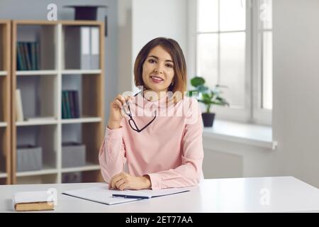 Female teacher sits in front of a webcam and conducts an online lesson via video chat. Stock Photo