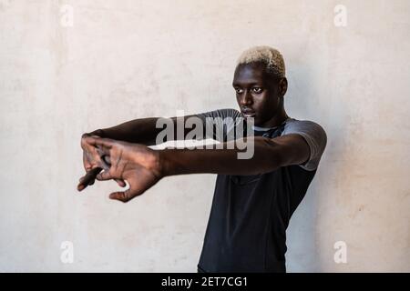Young athletic concentrated african american man stretching his body while doing workout indoors Stock Photo