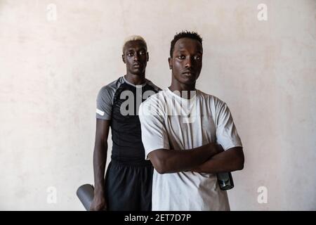 Two young african american men with exercise mats standing over wall indoors Stock Photo