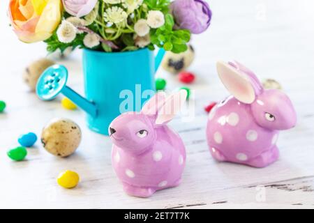 Happy Easter background with spring flowers, easter eggs, sweets and easter bunny on a white wooden background. Stock Photo