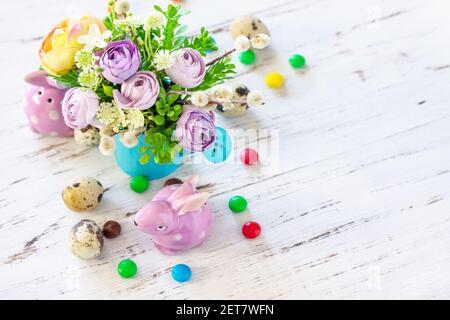Happy Easter background. Spring flowers, easter eggs, sweets and easter bunny on a white wooden background. Copy space. Stock Photo