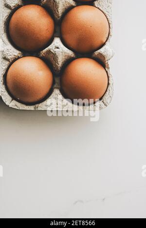 organic eggs in egg box on white marble kitchen table, closeup Stock Photo