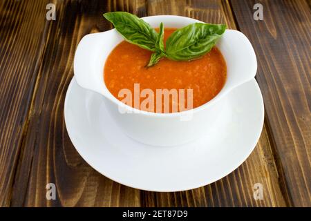 Tomato soup in the white bowl on the brown  wooden background.Closeup. Stock Photo