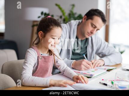 Father helping daugther with homework indoors at home, distance learning. Stock Photo
