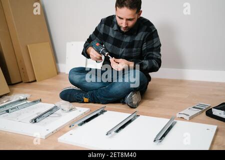 Man sitting on the floor assembling a piece of furniture. do it yourself Stock Photo