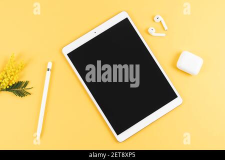 Tablet with headphones and pencil on yellow background. Top view. Copy space. Stock Photo
