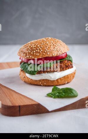 Vegan burger made with red beans, red pepper, spinach and white yoghurt. Fresh delicious vegetarian burger on a cutting board. Stock Photo