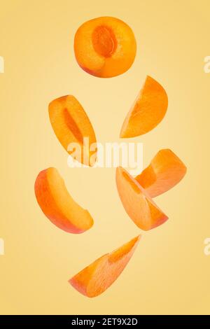 Falling down apricot slices isolated on trendy coloured background Stock Photo