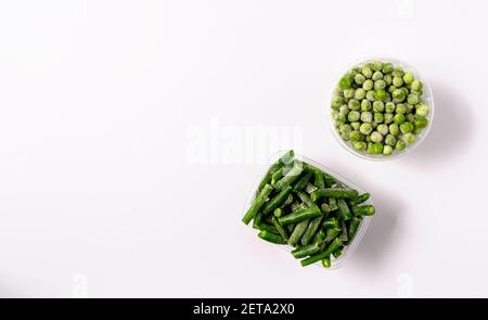 Frozen green beans and peas in plastic box isolated on white background,flat lay. Stock Photo