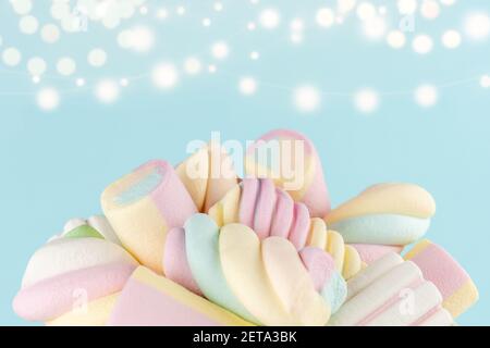 Marshmallows colorful chewy candy on blue bokeh background. Sweet holiday food concept. Stock Photo