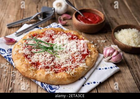 Classic Hungarian street food Langos, fried bread topped with ketchup, minced garlic and cheese on wooden background Stock Photo