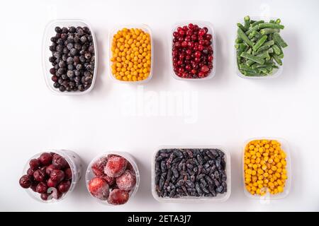 Frozen berries and vegetables in plastic boxes isolated on white background Stock Photo