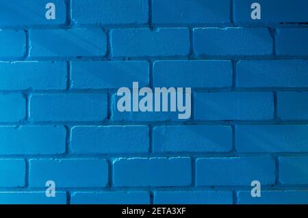 An old brick wall, painted blue, lit by the slanting rays of the sun. Stock Photo