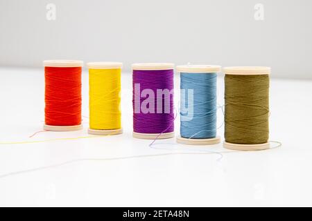 Five colorful thread spools isolated in the light background; intentional soft focus on violet co Stock Photo
