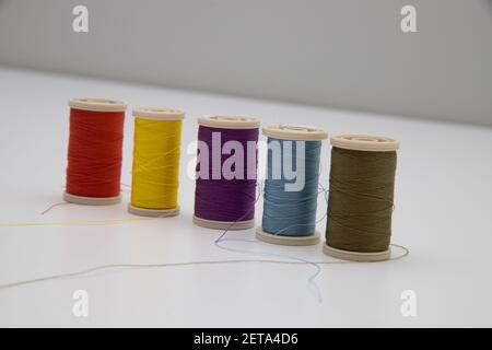A closeup of multi-colored thread spools in the light background; intentional soft focus on violet and light blue colors Stock Photo