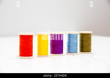 Five multi-colored thread spools isolated in the light background; intentional soft focus on violet and light blue colors Stock Photo