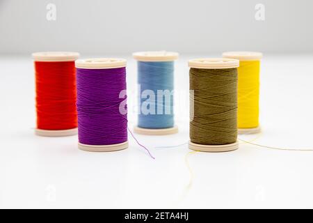 Five colorful thread spools isolated in the light background; intentional soft focus on violet and swamp colors Stock Photo