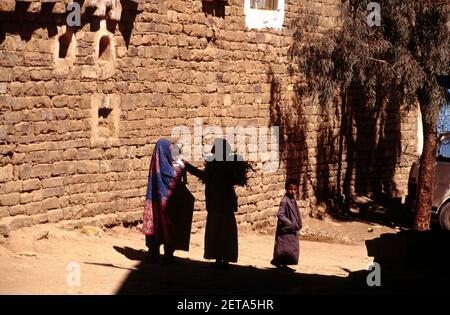 Woman Wearing Sana'ani Sitarah Dress holding Baby  Talking in the Street Thula Yemen Stock Photo