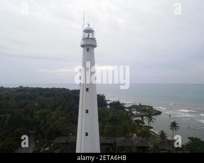 Aerial view of Lighthouse sea rock sunset landscape. Sunset lighthouse scene. At anyer beach with noise cloud and cityscape. Banten, Indonesia, March Stock Photo