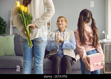 Joyful senior woman receives congratulations on Women's Day from her daughter and granddaughter. Stock Photo