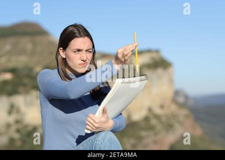 Draftswoman using pencil to calculate proportions drawing outdoors in the mountain Stock Photo