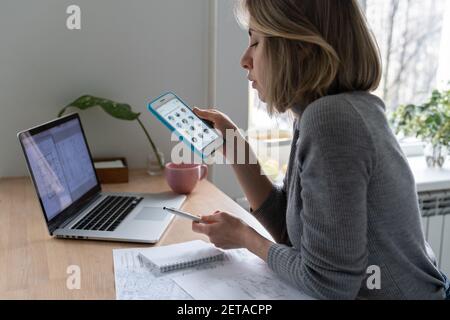 Woman designer using smartphone, takes a break from work and listens to speaker in clubhouse Stock Photo