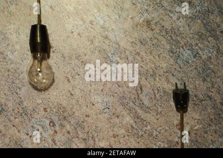 Frame formed by a vintage bulb hanging on a cable and its plug on a marble background. Concept of creativity and thinking. Mockup for innovative ideas Stock Photo