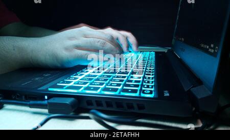 A selective focus shot of a man typing on a laptop keyboard - cybersecurity concept Stock Photo