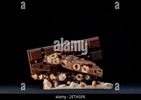 Dark and white chocolate with hazelnuts on a black background Stock Photo