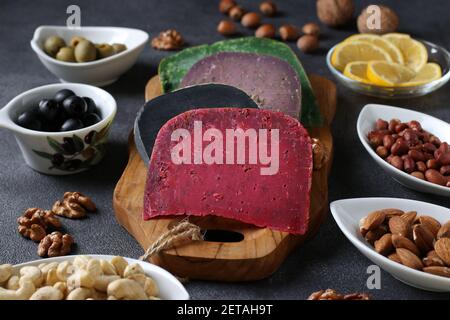 Multi colored gourmet cheese, olives, nuts and sliced lemon. Wine party snacks. Close-up Stock Photo