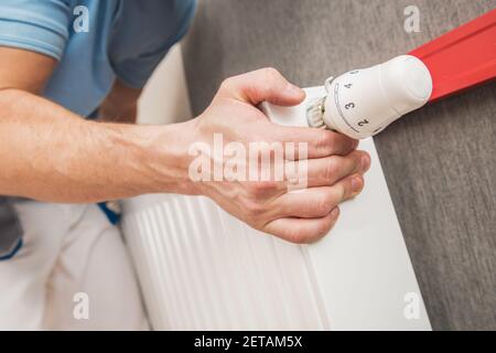 Caucasian Worker in His 40s Installing Heating Elements. Residential Heating Radiator Installation and Adjustment Close Up Photo. Stock Photo