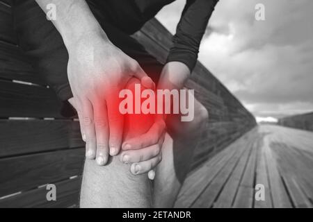 Man with knee pain, joint pain, arthritis or tendon problems. Runner holding and massaging his painful knee because of injury. Injury from exercising. Stock Photo