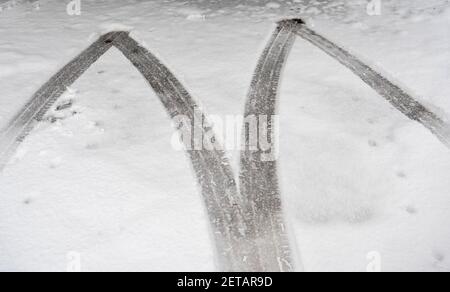 Distinct traces of tires on the asphalt covered with white snow early in the winter Stock Photo