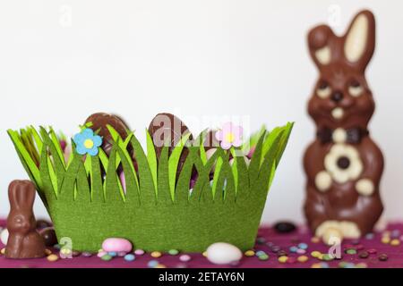 Easter basket with chocolate eggs, chocolate bunny and sweets on table Stock Photo