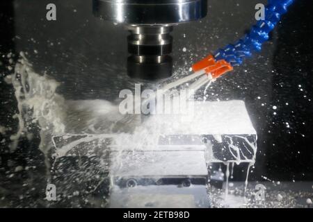 Milling process with coolant on a CNC machine. Milling process of aluminum using cutting fluid on a CNC milling machine. Selective focus. Stock Photo