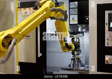 Robotic arm loads a workpiece into the CNC machine. Selective focus. Stock Photo