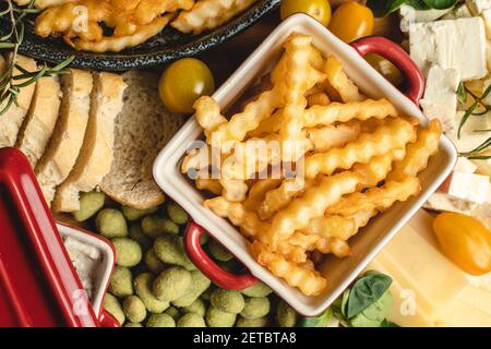 Top view on fresh baked potato chips french fries in the bowl on the plate with various food catering appetizer Stock Photo