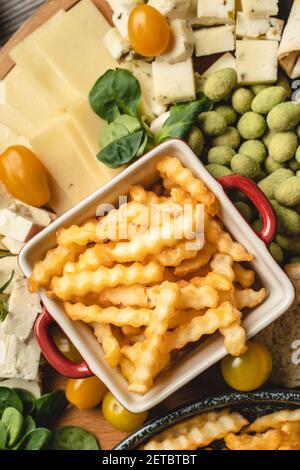 Top view on fresh baked potato chips french fries in the bowl on the plate with various food catering appetizer Stock Photo