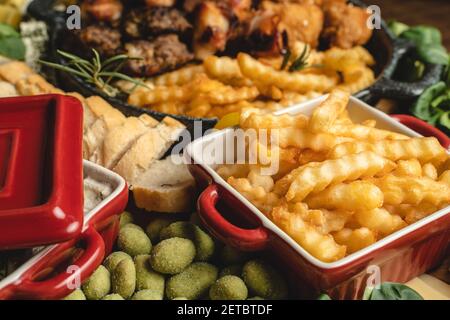 Close up view on fresh baked potato chips french fries in the bowl on the plate with various food catering appetizer Stock Photo