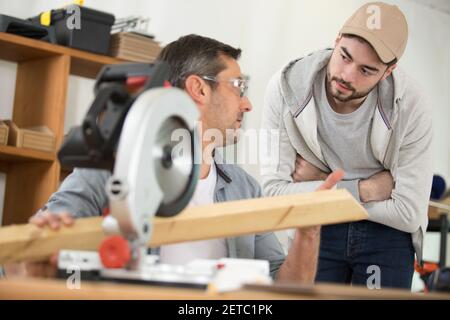 student and teacher in carpentry class using circular saw Stock Photo